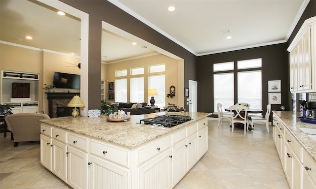 kitchen featuring black gas stovetop, light stone countertops, and crown molding