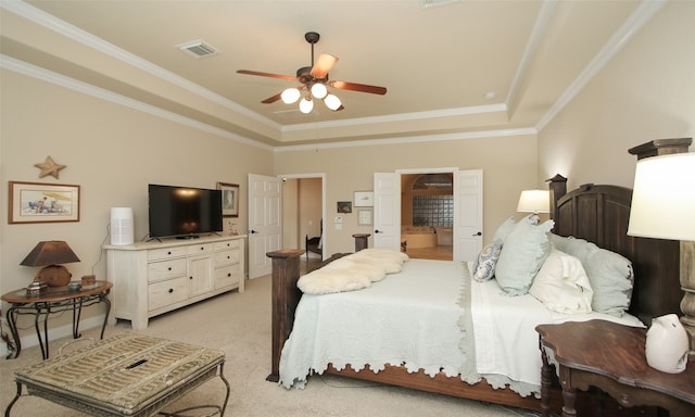 bedroom with ceiling fan, a raised ceiling, ornamental molding, light carpet, and ensuite bath