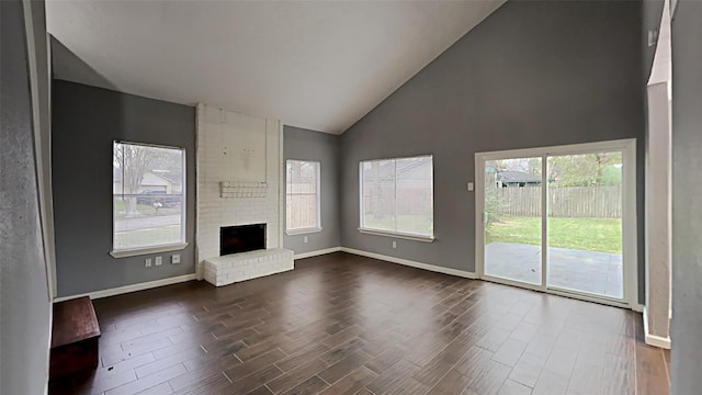 unfurnished living room with a brick fireplace, dark hardwood / wood-style flooring, and high vaulted ceiling