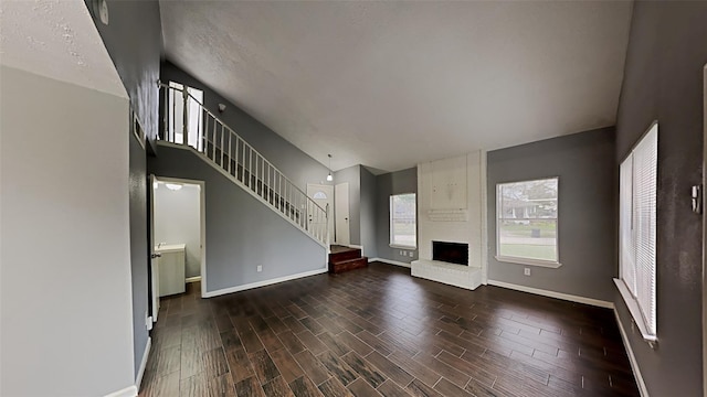 unfurnished living room with lofted ceiling, a fireplace, and dark hardwood / wood-style flooring