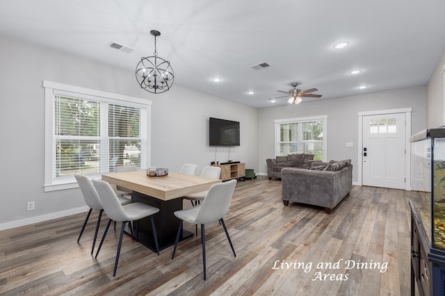 dining space with wood-type flooring, ceiling fan with notable chandelier, and a wealth of natural light