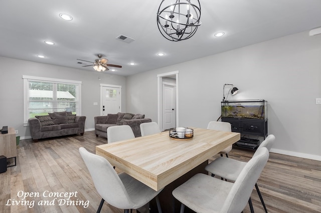 dining room featuring ceiling fan with notable chandelier and hardwood / wood-style floors