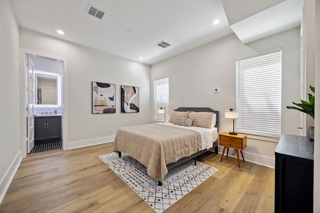 bedroom featuring connected bathroom, light hardwood / wood-style floors, and multiple windows