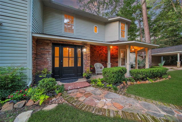 entrance to property featuring a lawn and covered porch