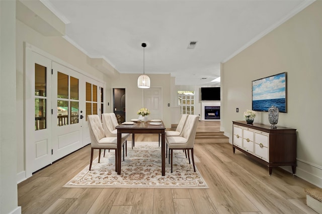 dining space featuring light wood-type flooring, crown molding, and a healthy amount of sunlight