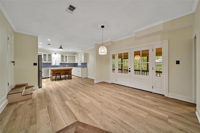 unfurnished living room featuring light hardwood / wood-style flooring and crown molding