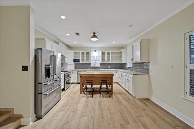 kitchen with stainless steel appliances, white cabinets, and light hardwood / wood-style floors