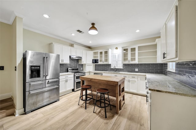 kitchen featuring white cabinets, ornamental molding, light hardwood / wood-style flooring, stainless steel appliances, and light stone countertops