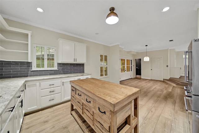 kitchen with light stone countertops, white cabinets, light hardwood / wood-style flooring, and decorative light fixtures