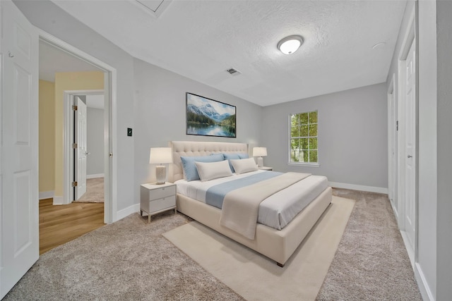 bedroom featuring light carpet and a textured ceiling