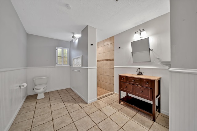 bathroom featuring a shower, vanity, a textured ceiling, tile patterned flooring, and toilet