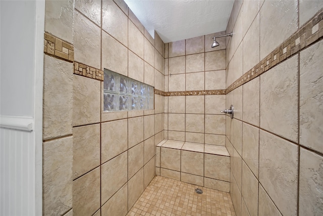 bathroom featuring a textured ceiling and a tile shower