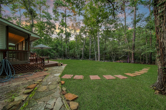 yard at dusk with a sunroom and a wooden deck