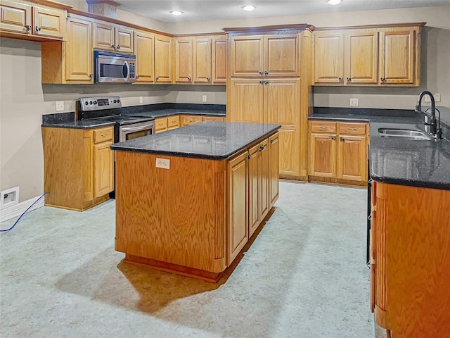 kitchen featuring dark stone countertops, a kitchen island, sink, and stainless steel appliances