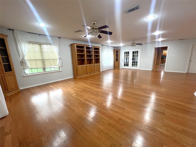 unfurnished living room featuring ceiling fan, a textured ceiling, and light hardwood / wood-style flooring