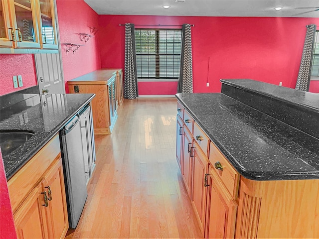 kitchen with dark stone countertops, dishwasher, and light hardwood / wood-style flooring