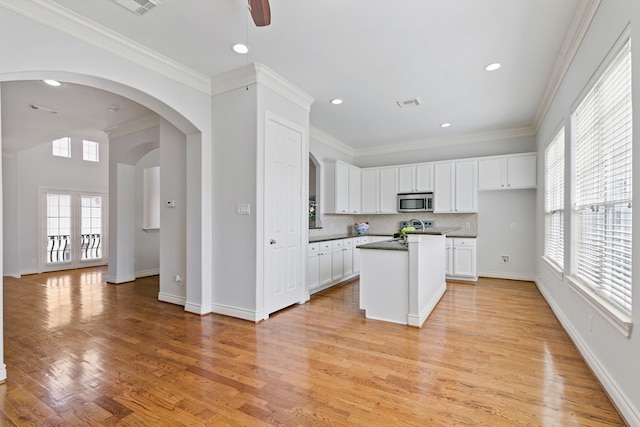 kitchen featuring white cabinets, a kitchen island, appliances with stainless steel finishes, and light wood-type flooring