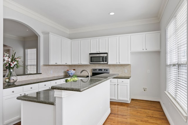 kitchen featuring stainless steel appliances, white cabinetry, light hardwood / wood-style floors, and a kitchen island with sink