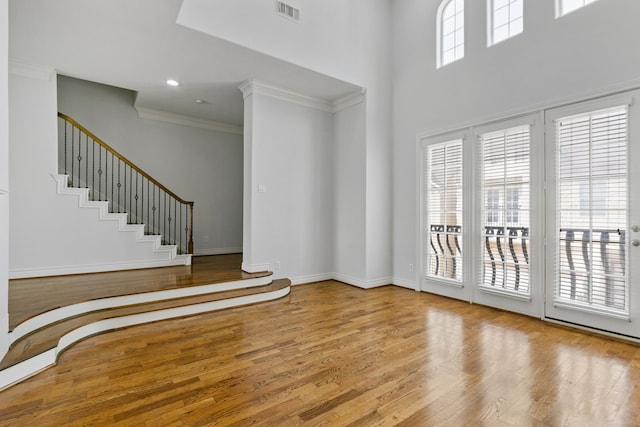 foyer entrance featuring light wood-type flooring, a high ceiling, and crown molding