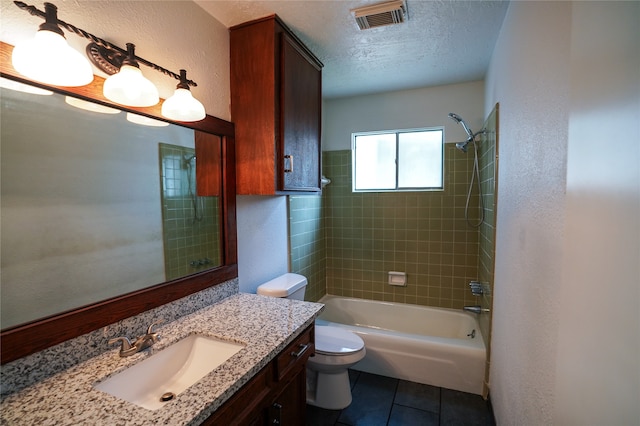 full bathroom with vanity, a textured ceiling, tile patterned flooring, toilet, and tiled shower / bath