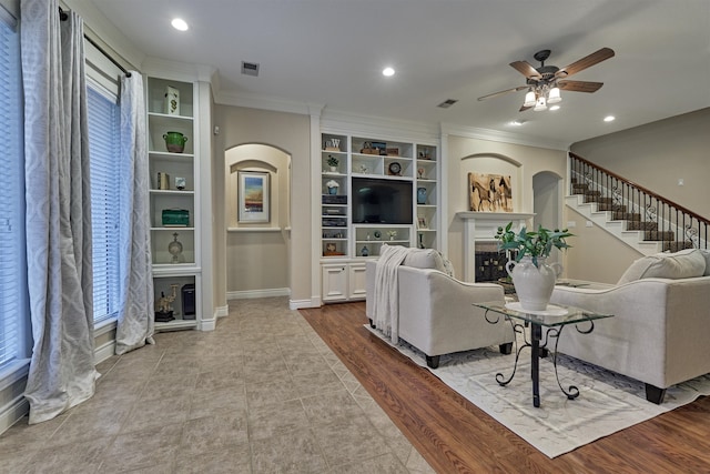 living room featuring ceiling fan, light wood-type flooring, and crown molding