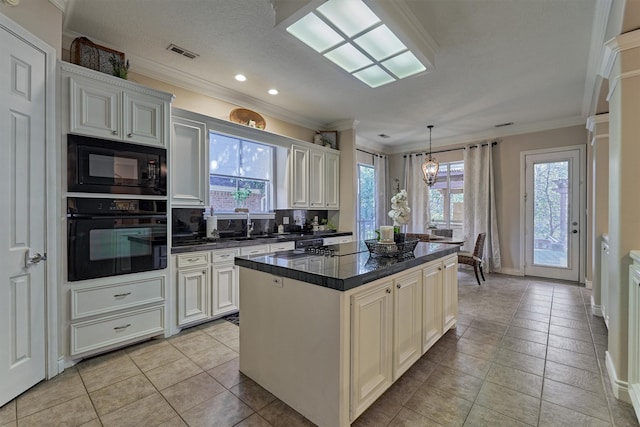 kitchen with backsplash, black appliances, decorative light fixtures, white cabinetry, and a kitchen island