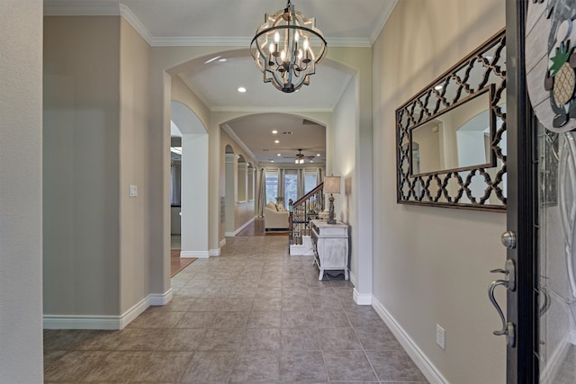 tiled entrance foyer with ceiling fan with notable chandelier and ornamental molding