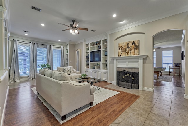 living room with ornamental molding, ceiling fan, light tile patterned floors, built in features, and billiards