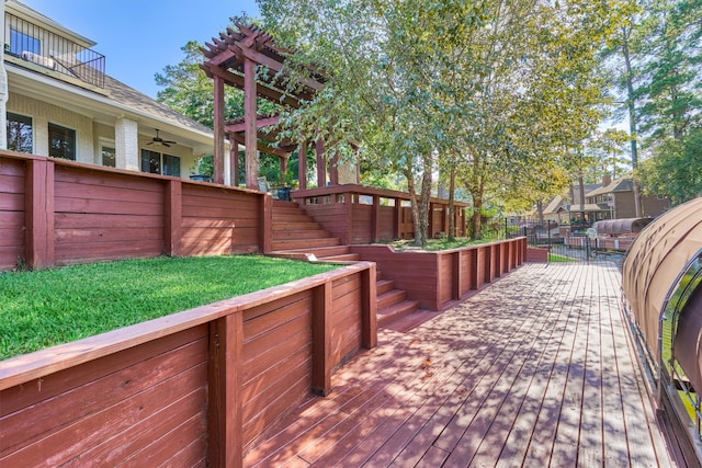 deck with ceiling fan, a pergola, and a yard