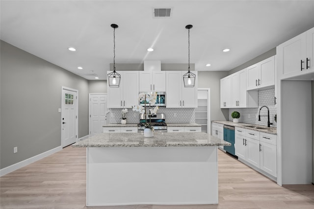 kitchen with sink, white cabinets, stainless steel appliances, and a kitchen island