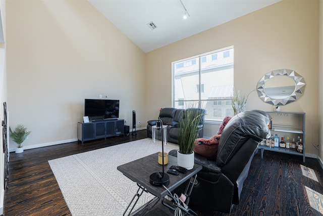 living room with track lighting, dark wood-type flooring, and vaulted ceiling