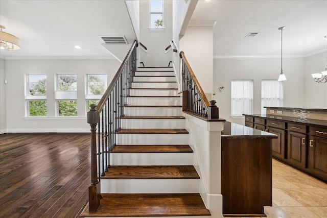 staircase featuring a notable chandelier, crown molding, plenty of natural light, and hardwood / wood-style flooring