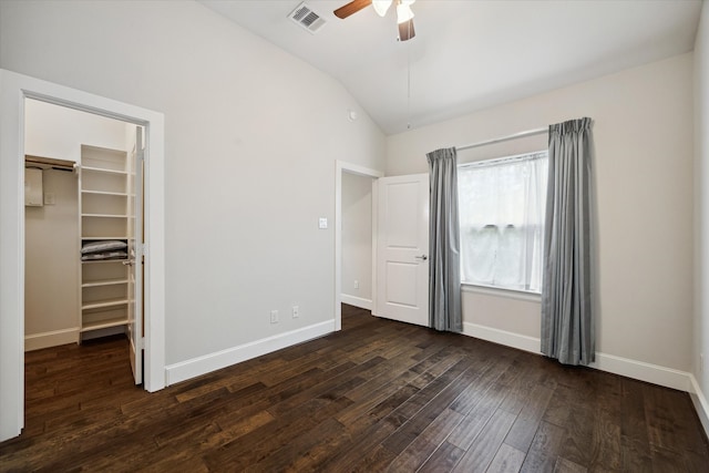 unfurnished bedroom featuring vaulted ceiling, a closet, ceiling fan, a walk in closet, and dark hardwood / wood-style floors