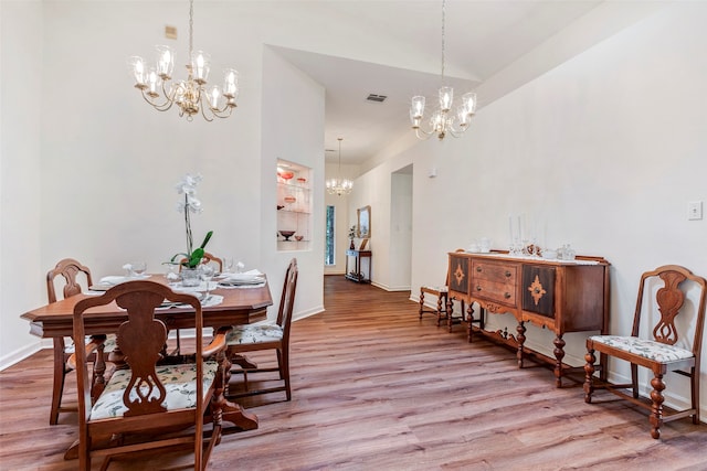 dining area with lofted ceiling, an inviting chandelier, and light hardwood / wood-style flooring