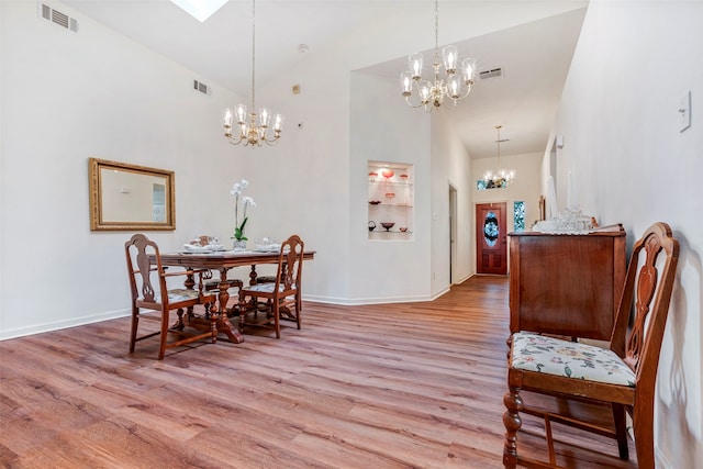 dining area featuring high vaulted ceiling, a chandelier, and light hardwood / wood-style floors