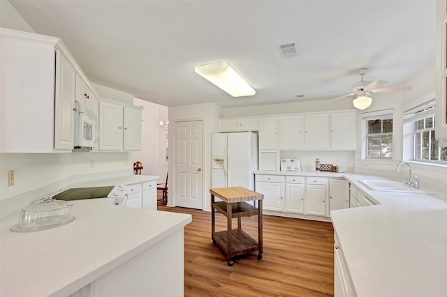 kitchen with light hardwood / wood-style floors, sink, white appliances, and white cabinetry