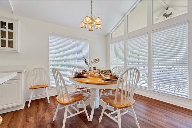 dining area featuring ceiling fan with notable chandelier, a healthy amount of sunlight, vaulted ceiling, and dark hardwood / wood-style floors