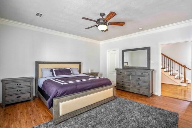 bedroom featuring hardwood / wood-style flooring, ceiling fan, and crown molding