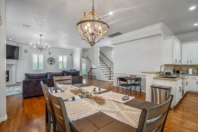 dining space with a chandelier, hardwood / wood-style floors, ornamental molding, and sink