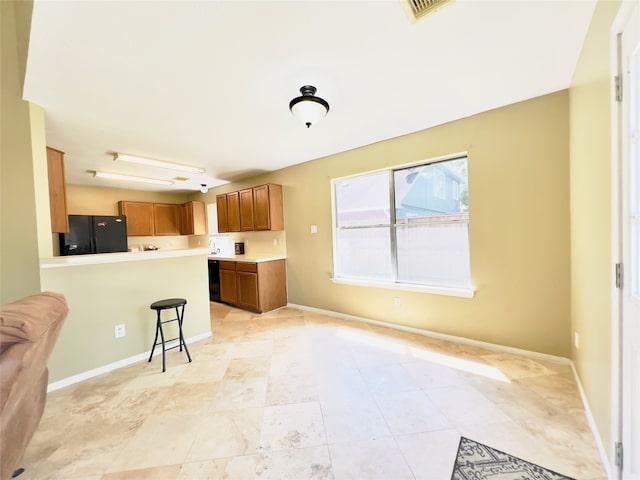 kitchen featuring kitchen peninsula, a kitchen breakfast bar, and black appliances