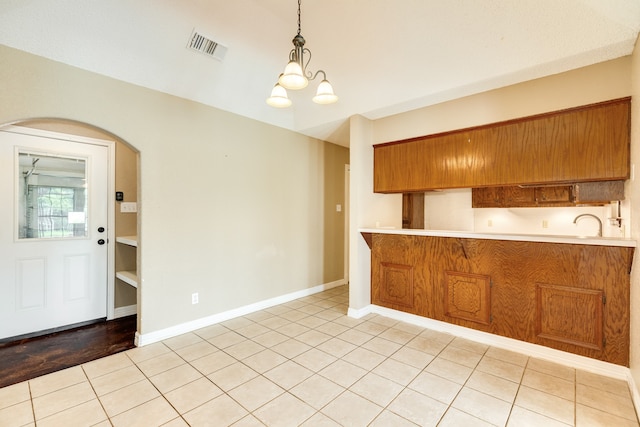 kitchen with hanging light fixtures, light hardwood / wood-style floors, kitchen peninsula, and a chandelier