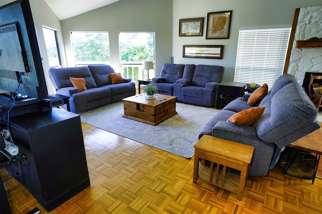 living room featuring a stone fireplace, vaulted ceiling, and light parquet floors