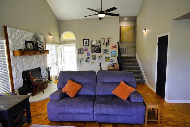 living room featuring a fireplace, high vaulted ceiling, ceiling fan, and dark parquet floors