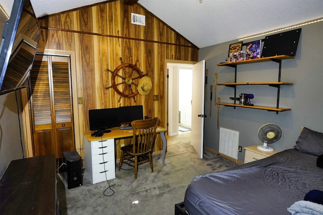 carpeted bedroom with lofted ceiling, wood walls, and a closet