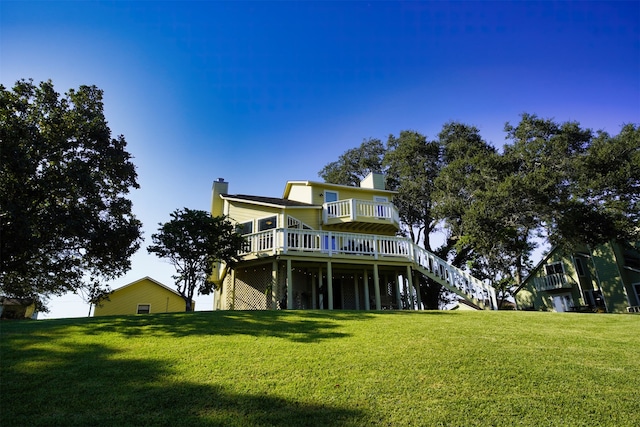 rear view of house with a wooden deck and a yard