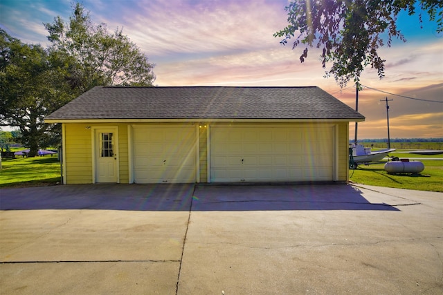 garage at dusk featuring a lawn