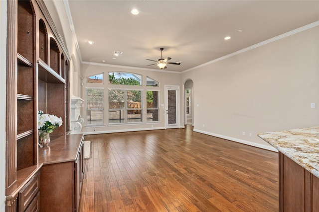 unfurnished living room with ceiling fan, dark wood-type flooring, and crown molding