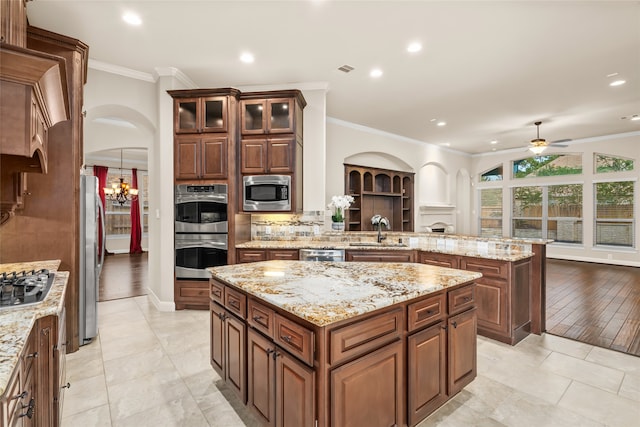 kitchen featuring ceiling fan with notable chandelier, stainless steel appliances, a center island, light hardwood / wood-style flooring, and sink