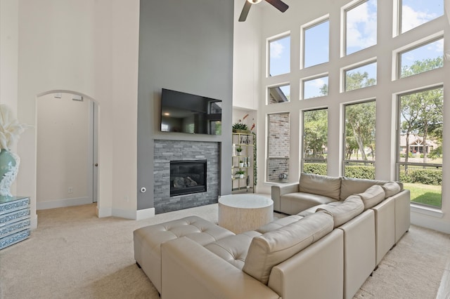 carpeted living room featuring a towering ceiling, ceiling fan, and a wealth of natural light