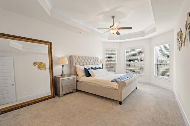 bedroom featuring crown molding, a tray ceiling, ceiling fan, and light colored carpet